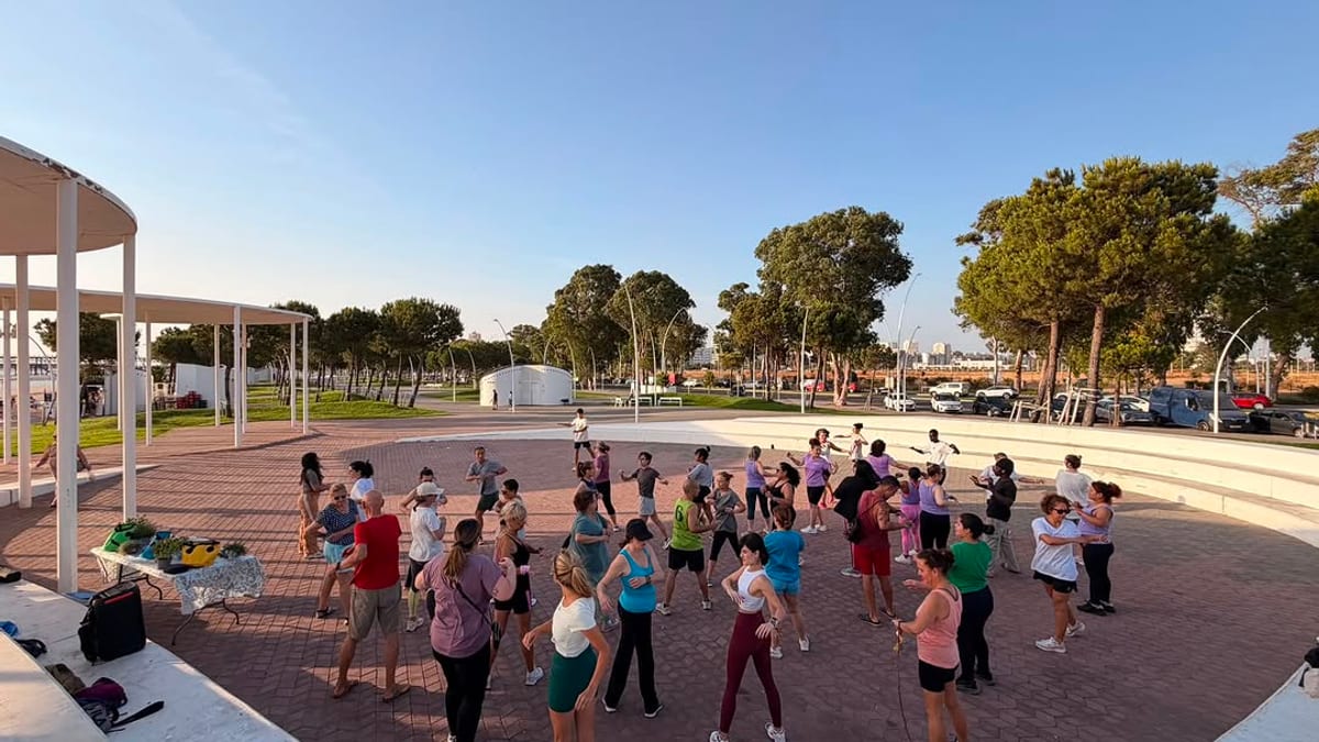 Participantes realizando ejercicio grupal al atardecer en el Paseo de la Ría durante la sesión del taller Movernos para sentirnos mejor