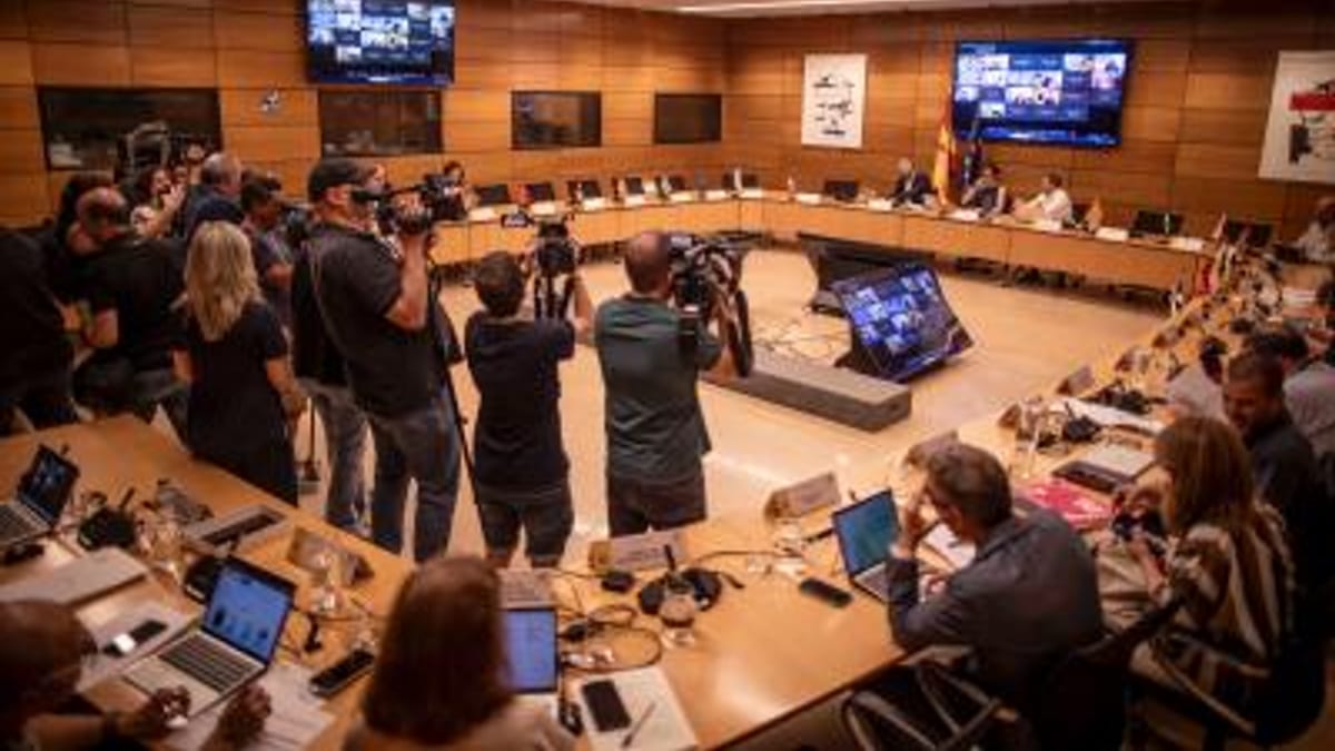 Reunión del Consejo Interterritorial del Sistema Nacional de Salud con participantes alrededor de mesa en U, tecnología y dispositivos de comunicación