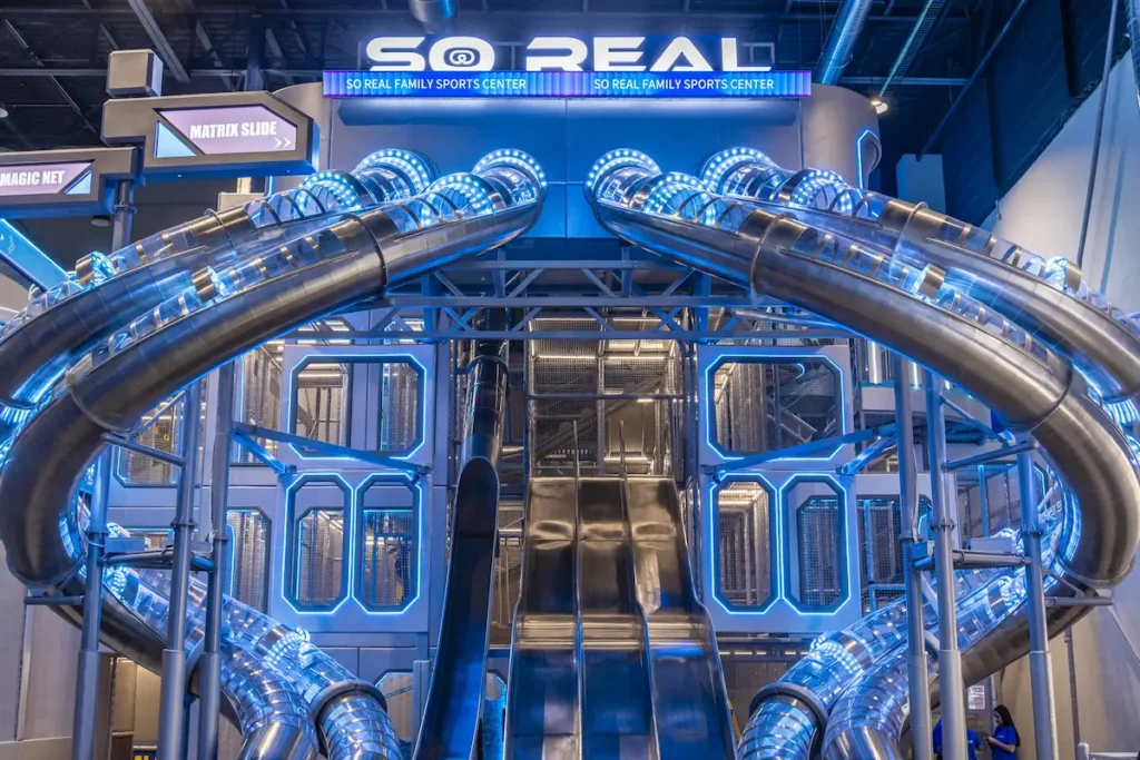 Grandes toboganes de tubo con luces LED azules en la estructura principal del So Real Family Sports Center.