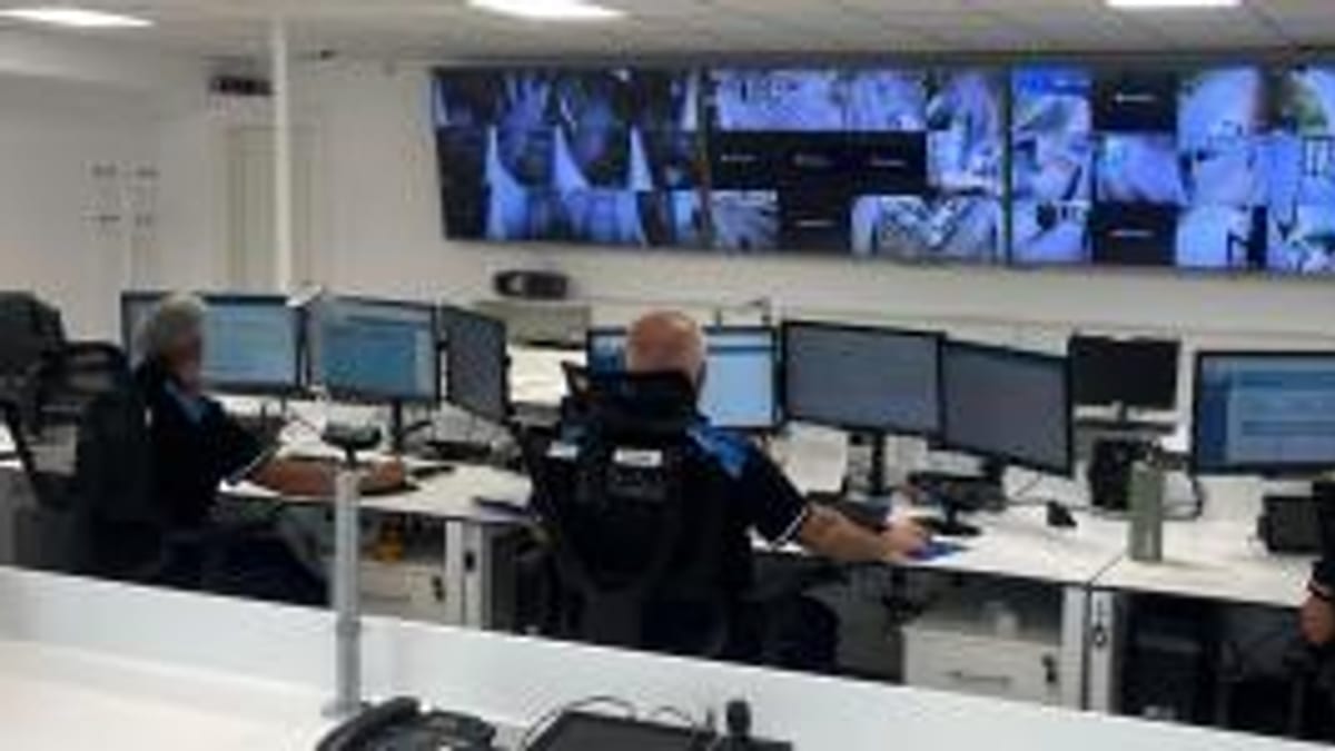 Centro de control y monitoreo con operarios en estaciones de computadoras y pantallas de vigilancia para servicios de seguridad