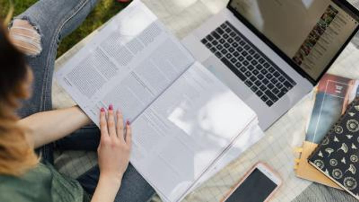 Persona trabajando con documentos, laptop y materiales de escritorio en una mesa de trabajo