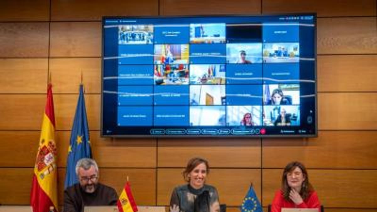 Conferencia oficial sobre aprobación de programas de cohesión sanitaria y vigilancia de la salud con participantes en mesa y banderas españolas y europeas