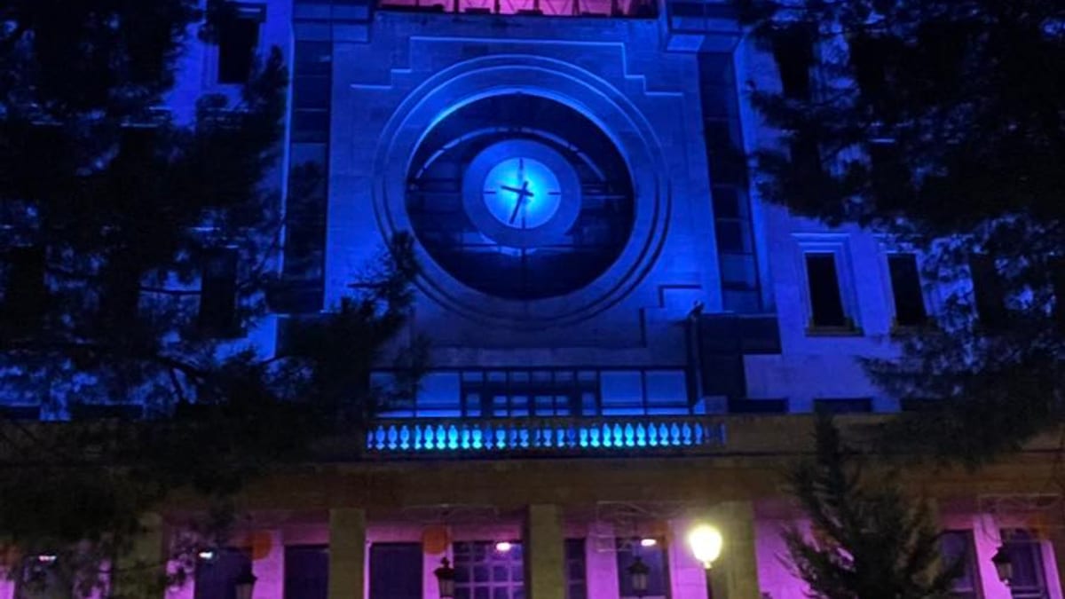 Fachada de edificio histórico iluminado de noche con luz azul y rosa en conmemoración del Día Internacional de Duelo Gestacional, Perinatal y Neonatal