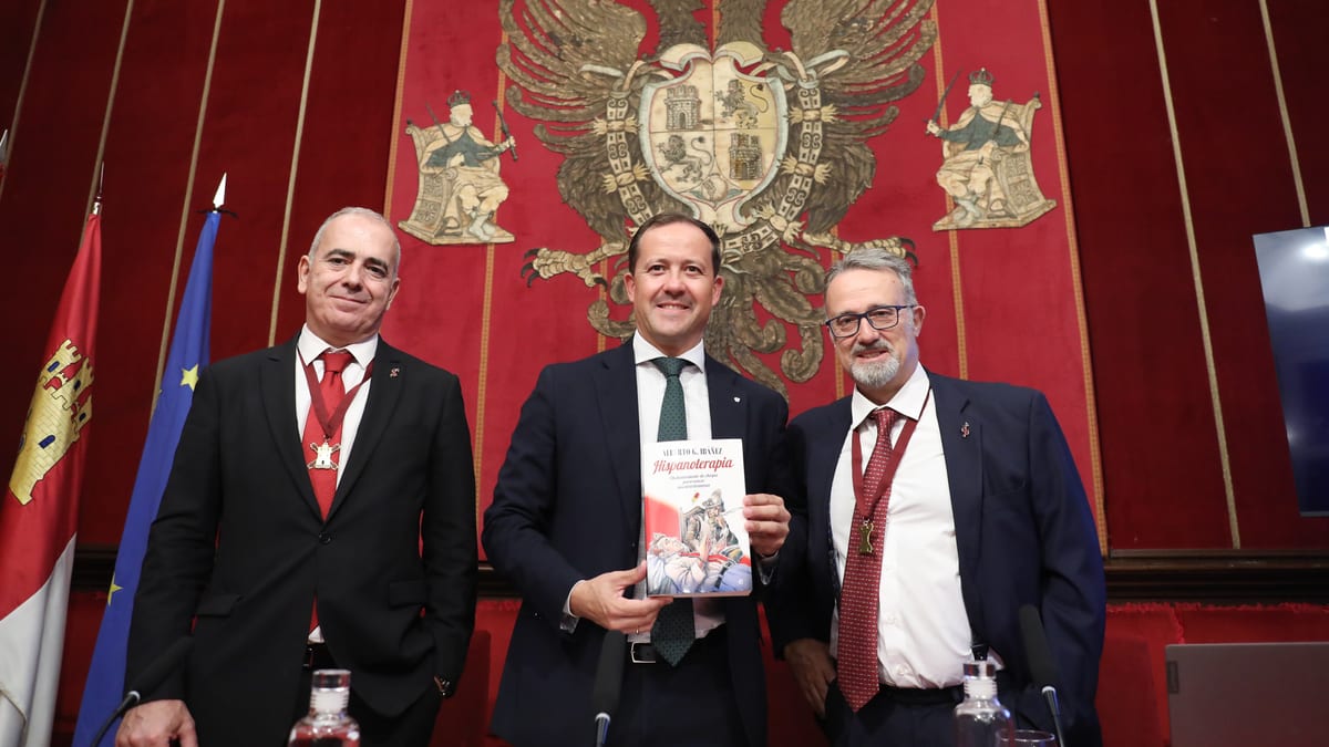Alberto G. Ibáñez en la Sala Capitular de Toledo durante la presentación de 'Hispanoterapia', sosteniendo la obra frente al escudo heráldico