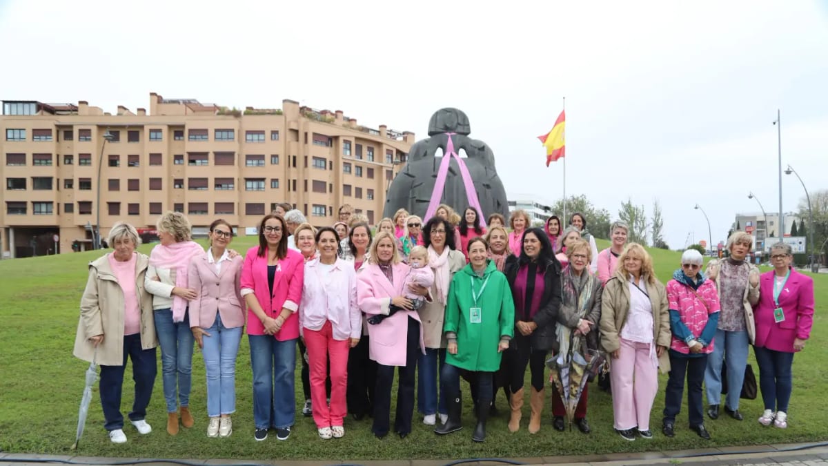 Grupo de mujeres posando frente a una estatua con el Ayuntamiento de Alcobendas al fondo durante la conmemoración del Día Mundial del Cáncer de Mama Metastásico