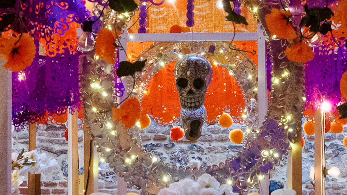 Altar mexicano del Día de Muertos con flores, velas y elementos decorativos tradicionales en un espacio cultural de Madrid