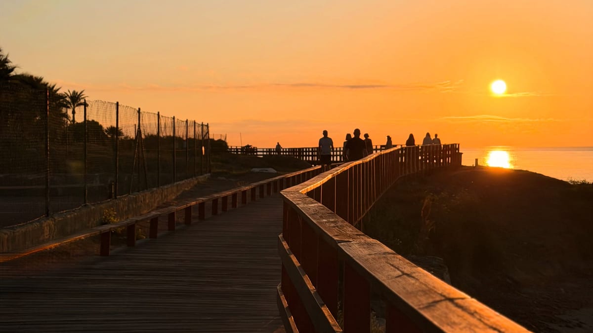 Amanecer en la Senda Litoral de Málaga con el sol asomando sobre el Mediterráneo y los primeros paseantes junto al mar
