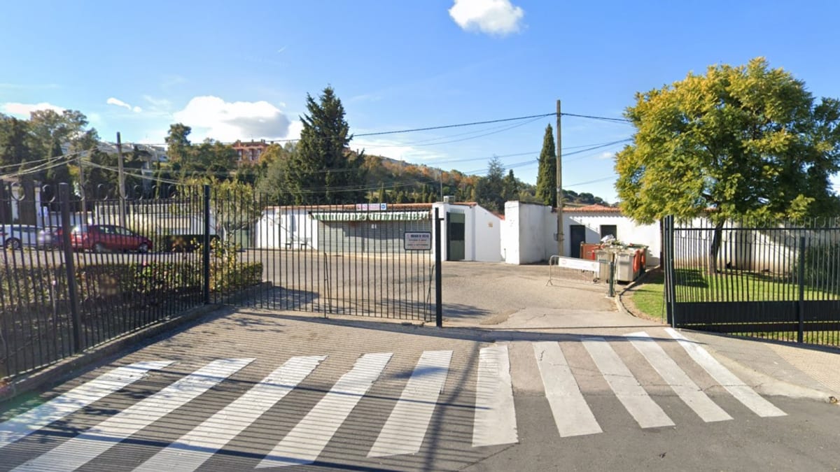 Entrada principal del cementerio de Cáceres con puertas metálicas y áreas verdes
