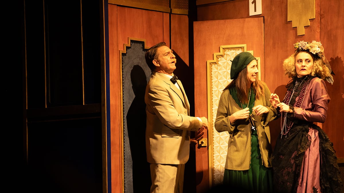 Escena teatral de Asesinato en el Orient Express con cuatro actores en escenario con decoración art déco en tonos naranjas
