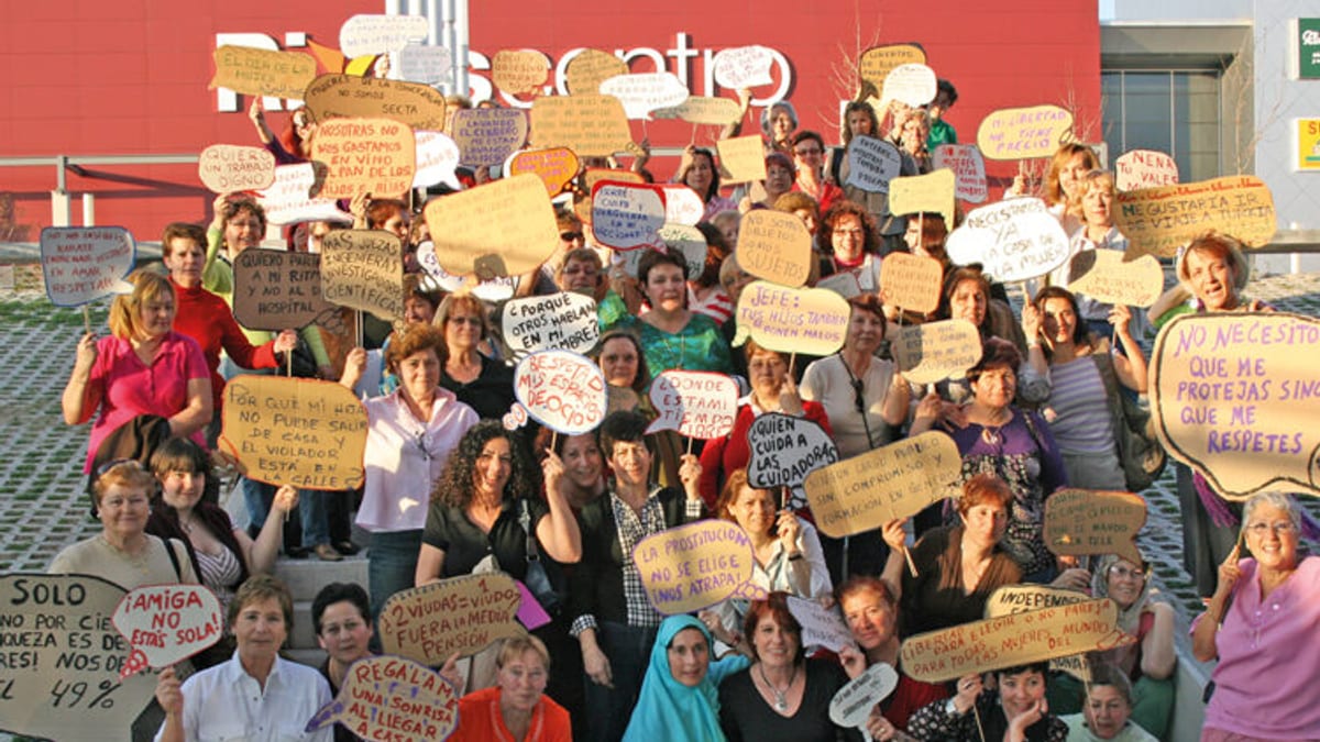 Fotografía de una manifestación con participantes sosteniendo carteles de protesta con mensajes escritos a mano