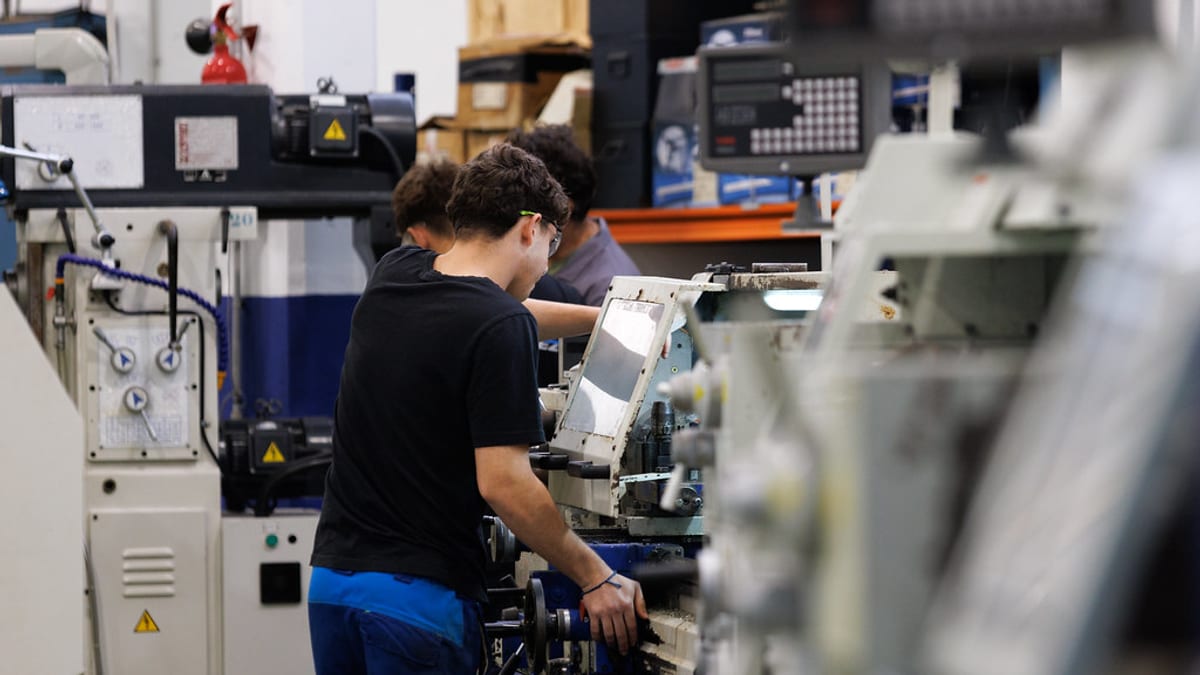 Personas trabajando en una instalación industrial con maquinaria, representando la Formación Profesional