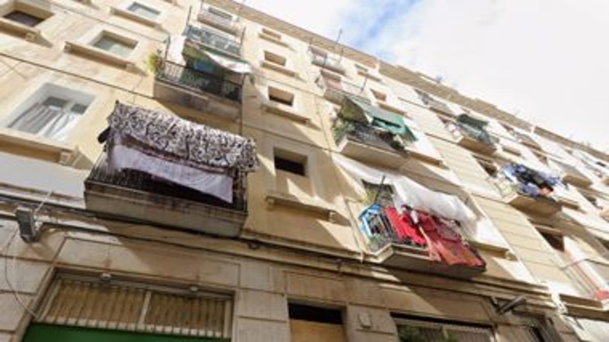 Fachada de un edificio de apartamentos en el Raval con balcones, ropa tendida y plantas