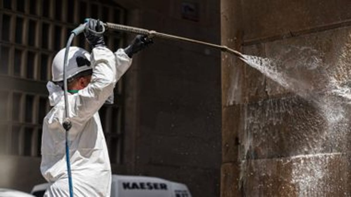Operario limpiando una pared con pintadas en Barcelona