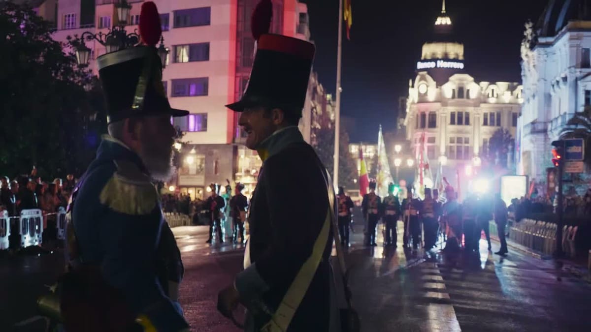 Escena nocturna de la recreación de las batallas del Desarme en Oviedo con participantes en trajes históricos en una calle iluminada