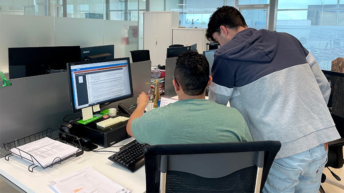 Dos profesionales en ambiente de oficina trabajando ante un monitor de computadora