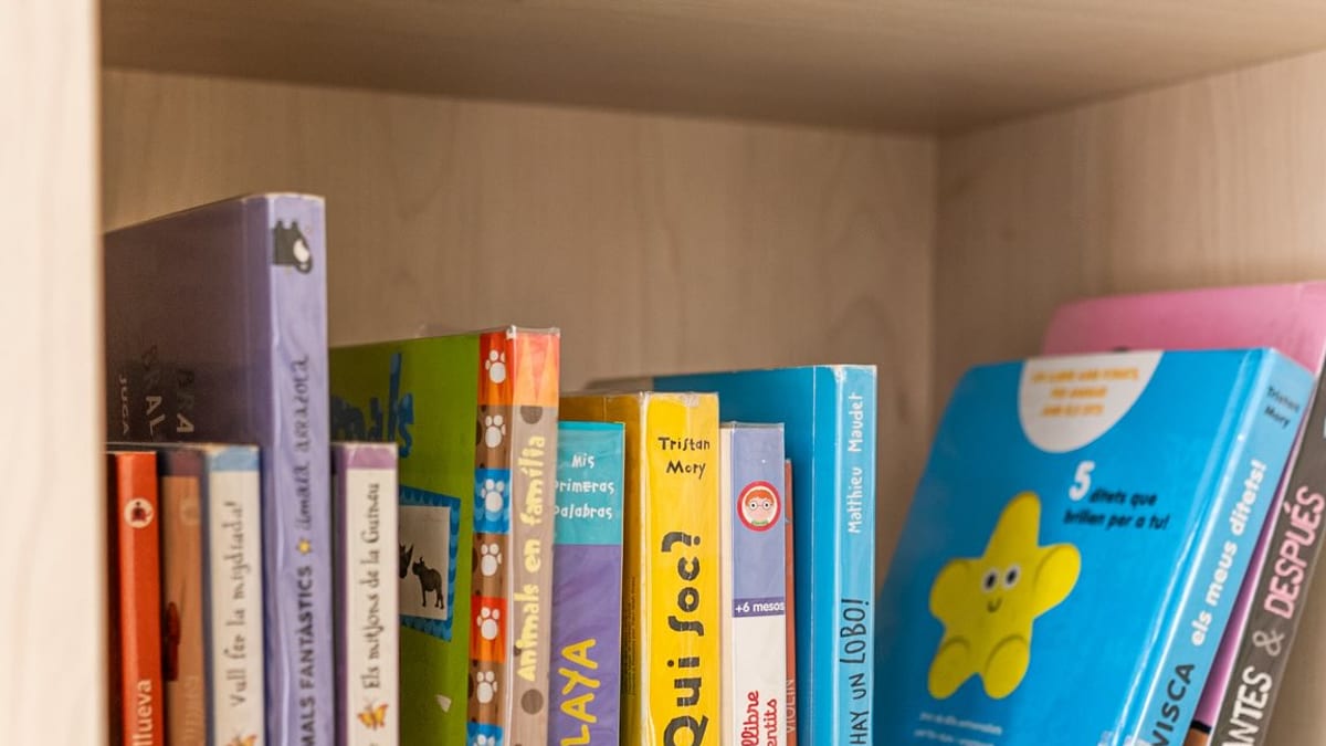 Estantería de madera con libros infantiles de diversos colores y títulos en una biblioteca