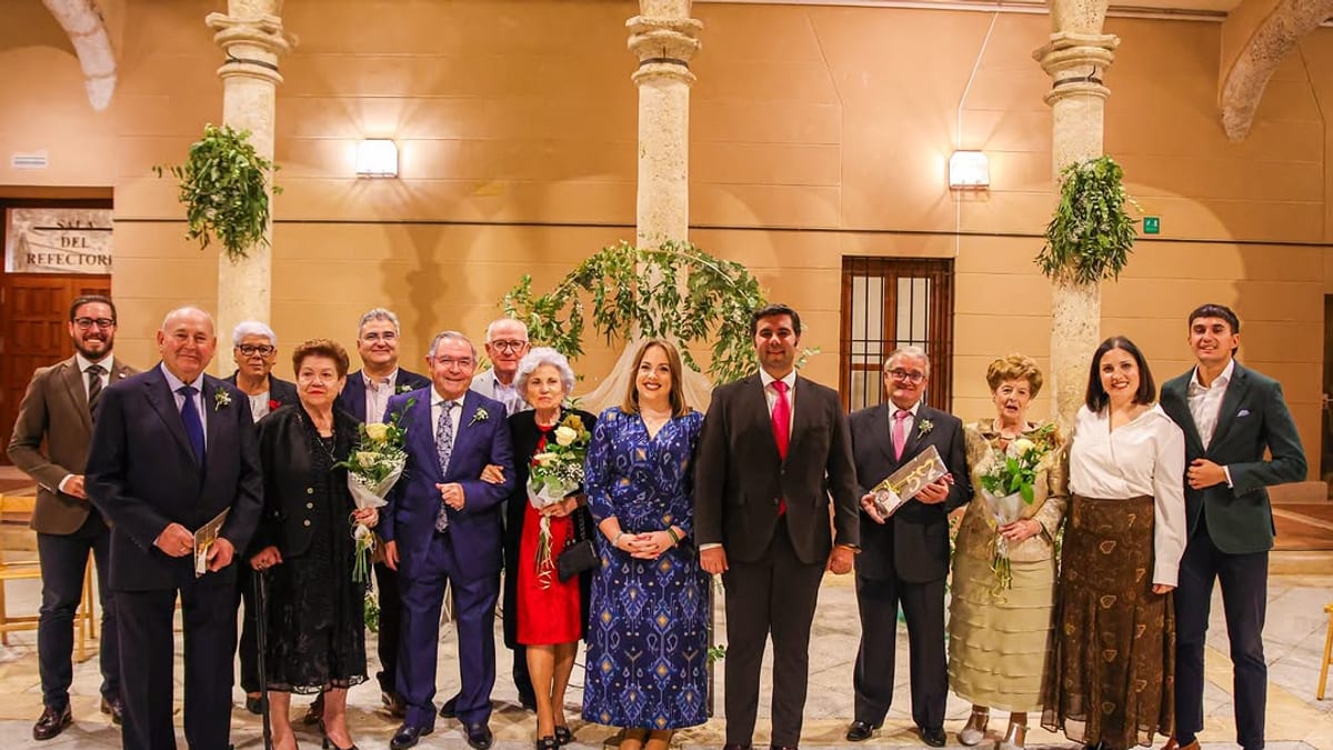 Grupo de personas posando en el Palacio de Pedro I de Torrijos durante el acto de homenaje a las bodas de oro, con flores y documentos commemorativos