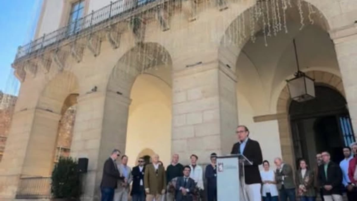 Acto conmemorativo del Día Mundial contra la Poliomielitis en el Ayuntamiento de Cáceres con asistentes frente al edificio histórico