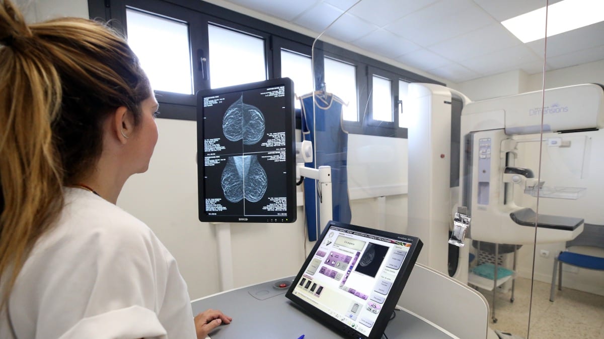 Profesional sanitaria observando imágenes de mamografía en pantallas de radiología