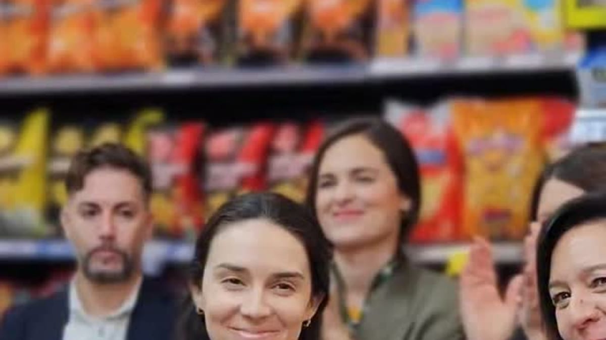 Grupo de personas en evento de inauguración de Carrefour Express con estanterías de productos al fondo