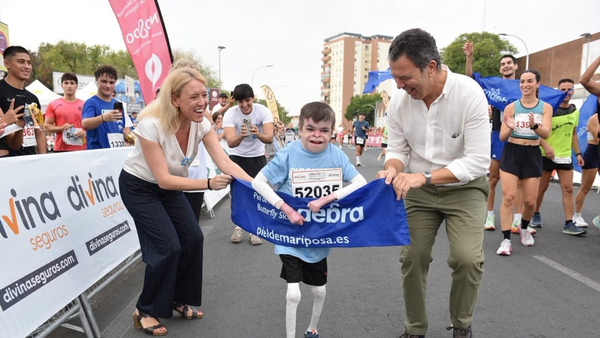 Participantes en la Carrera Nervión-San Pablo de Sevilla del Circuito Divina Seguros, con Leo sosteniendo una pancarta de la asociación Debra