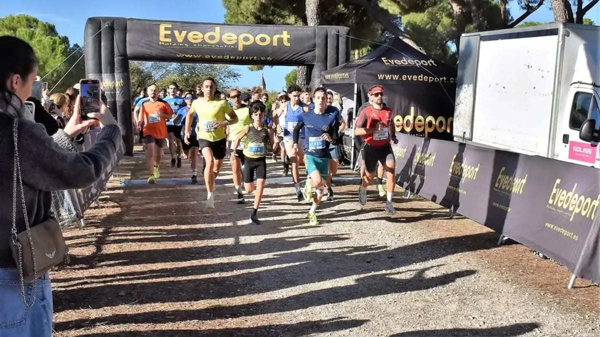 Participantes de la Carrera Popular de Villaviciosa de Odón corriendo en la calle con ambiente festivo y deportivo