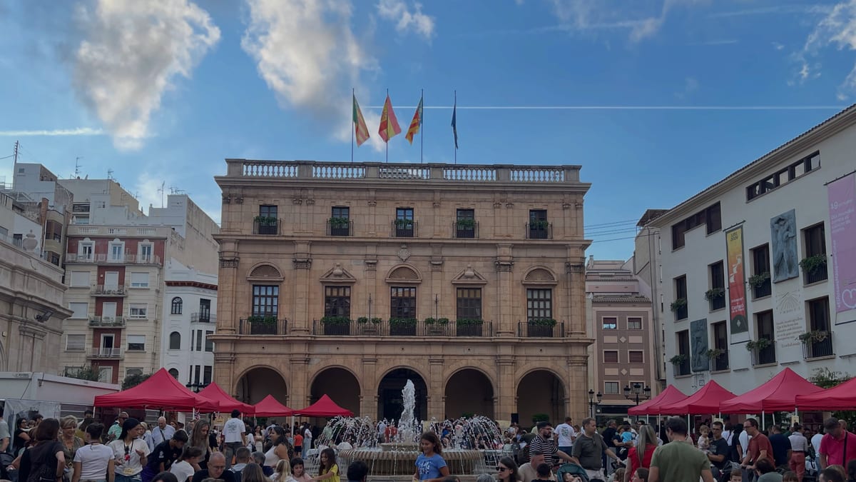 Plaza Mayor de Castellón durante el Día de Juegos con público, carpas rojas, mesas de juego y edificio histórico al fondo