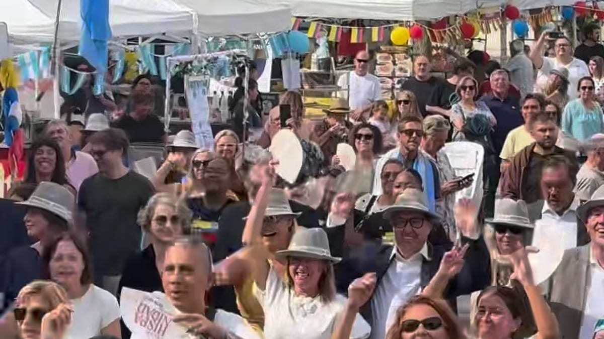 Multitud de personas en jornada de celebración de Hispanidad en Castellón con carpas blancas y bandera azul y blanca