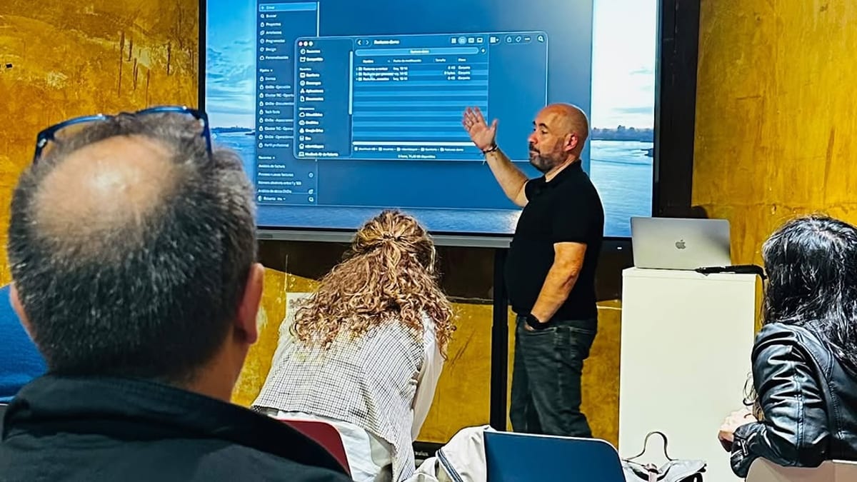 Sesión de charlas sobre inteligencia artificial aplicada al negocio en Oviedo, con instructor señalando pantalla de presentación en sala con paredes amarillas
