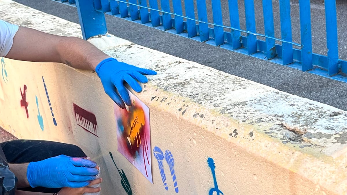 Persona trabajando en mural artístico del colegio Cristóbal Colón para la iniciativa Deja tu huella en el cole