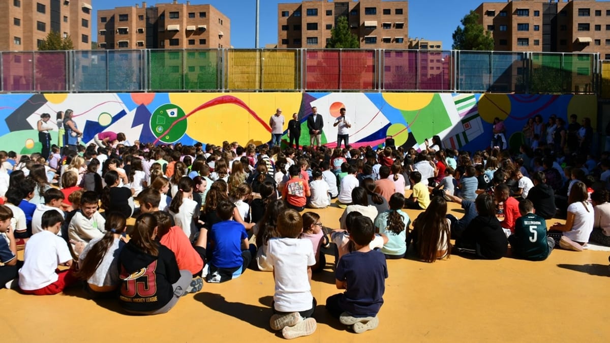 Acto de conmemoración del Día de la Niña en el CEIP Isaac Albéniz de Cuenca con asistentes sentados en la explanada del colegio