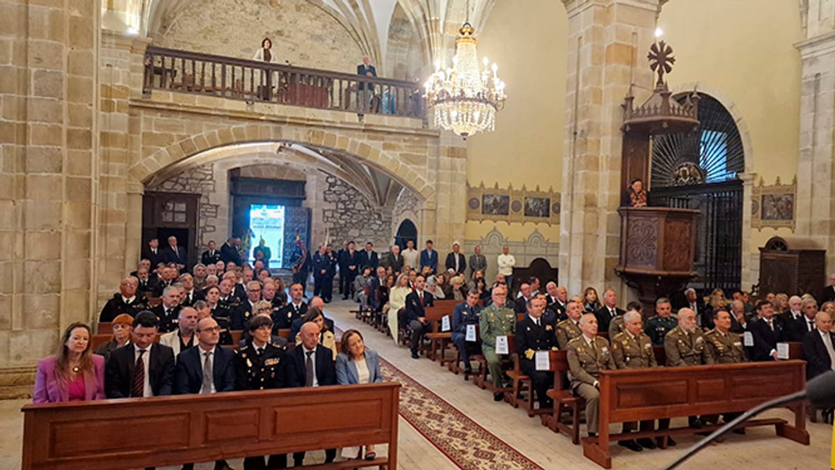Interior de una iglesia con asistentes en los bancos durante el acto de reconocimiento de la Asociación Cultural Santiago, con la bandera española visible