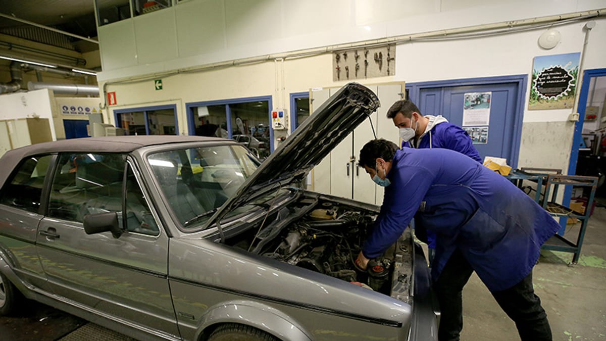 Taller mecánico con dos profesionales trabajando en un automóvil, representando la formación práctica en Formación Profesional