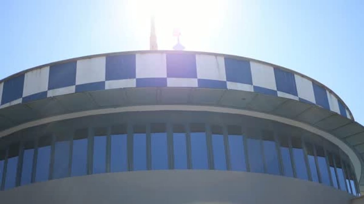 Estructura arquitectónica moderna con forma circular, patrón de cuadros azules y blancos en borde superior y grandes ventanas