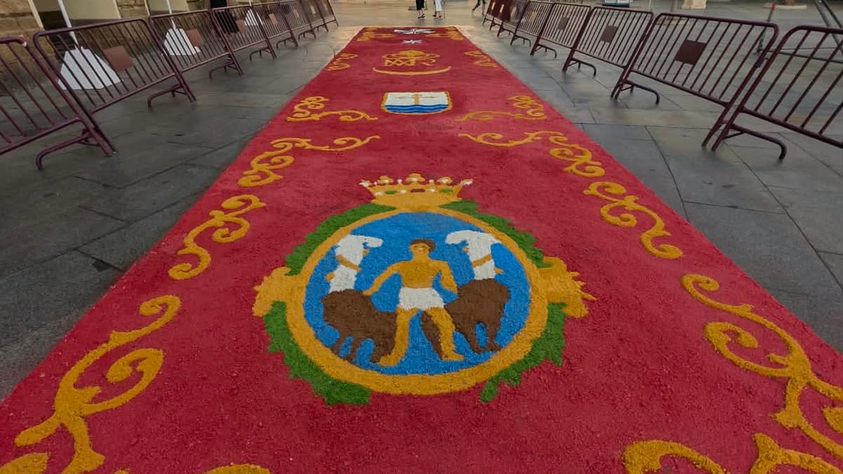 Alfombra ceremonial roja con decoraciones doradas y escudo heráldico en una plaza de Cádiz durante las celebraciones de la Patrona