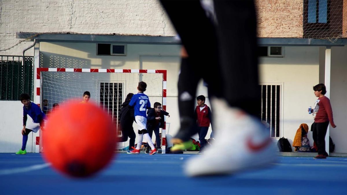 Niños jugando en una cancha de futsal durante una actividad deportiva