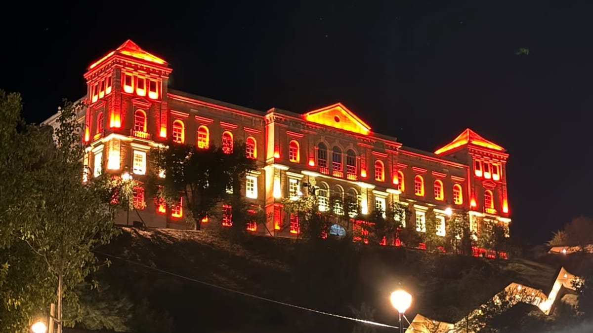 Fachada del Palacio Provincial de Toledo iluminada de rojo y gualda al atardecer