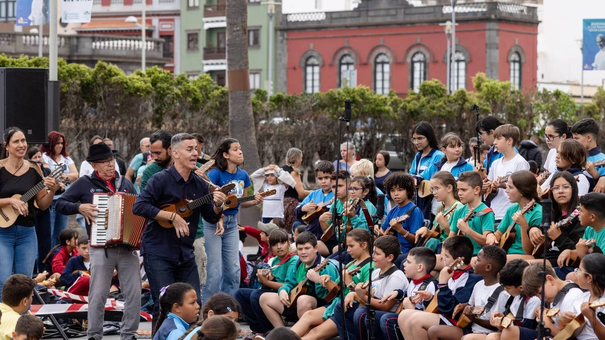 Evento musical del proyecto Un Timple en mi Cole con múltiples músicos y alumnos de Primaria participando en actividades educativas al aire libre