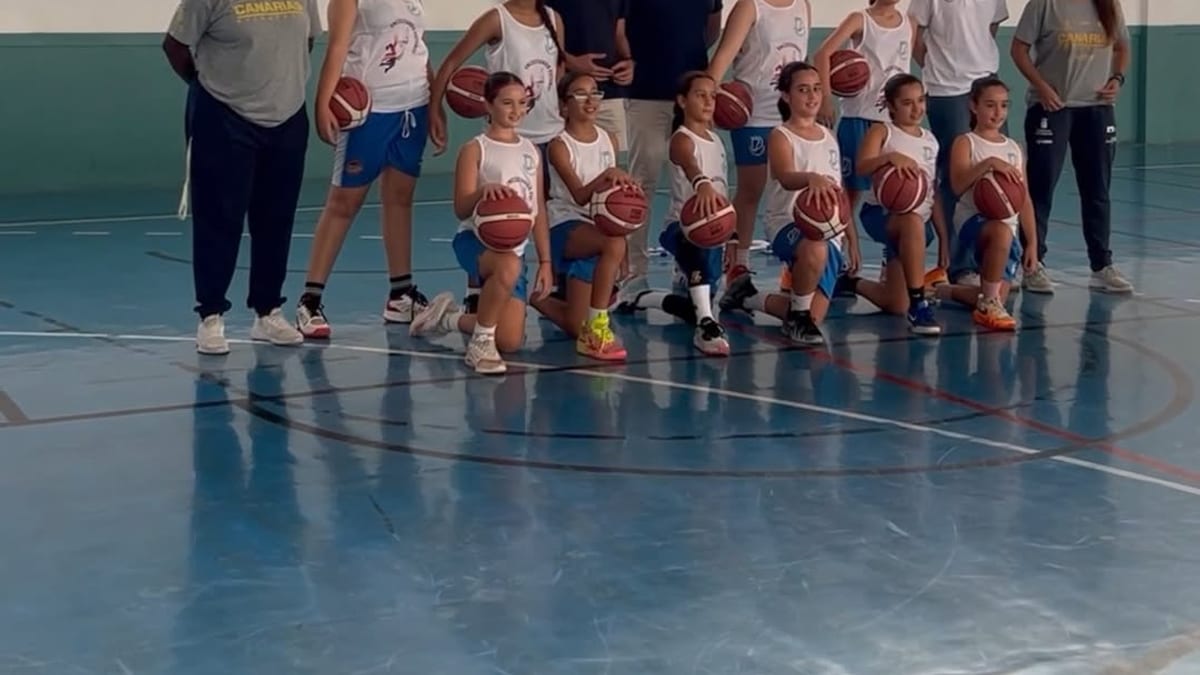 Grupo de jóvenes jugadores de baloncesto femenino con entrenadores en una cancha de gimnasio durante el programa Encestando Futuros