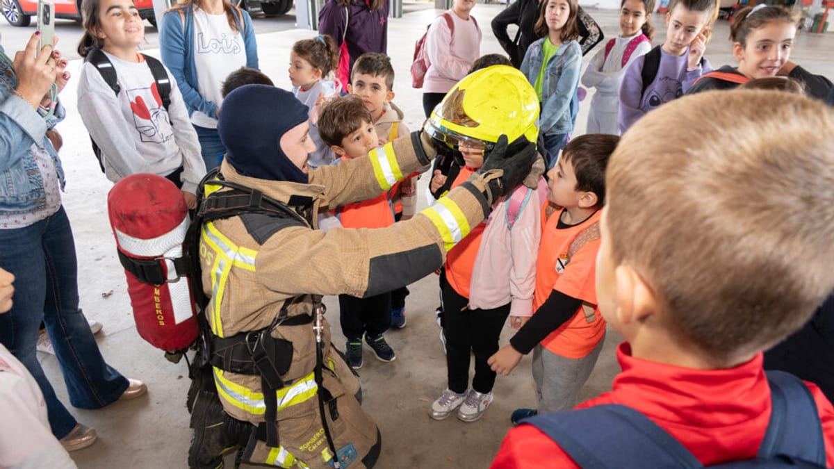 Bombero demostrando equipo de seguridad a un grupo de escolares en el parque móvil del SEPEI