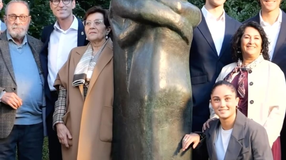 Grupo de personas posando junto a la escultura de bronce 'El abrazo' de Félix Reyes en un jardín de Baños de río Tobía