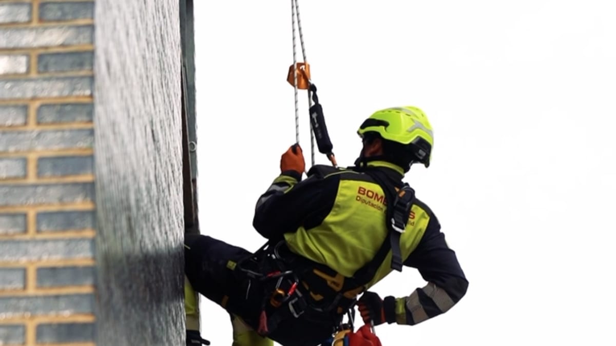 Bombero formador Miguel instruye a Laro, nuevo bombero, en técnicas de trabajo en altura y rescate durante la formación provincial