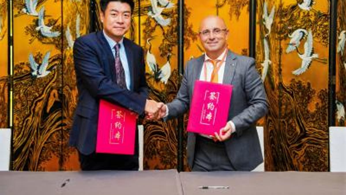 Dos hombres en traje sostienen documentos rojos durante la firma del acuerdo entre la Generalitat Valenciana y asociación industrial de Jiangsu