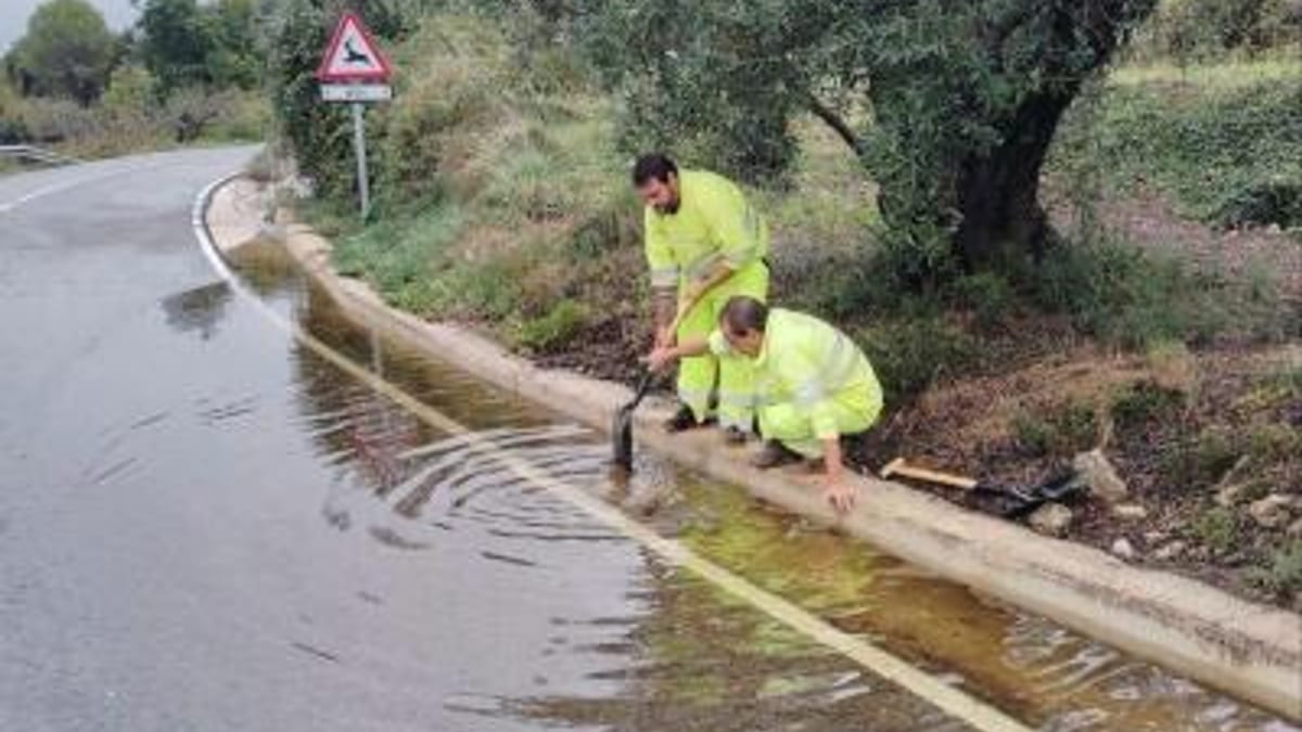 Trabajadores con chalecos de seguridad trabajando en tareas de reparación junto a un cuerpo de agua afectado por la dana