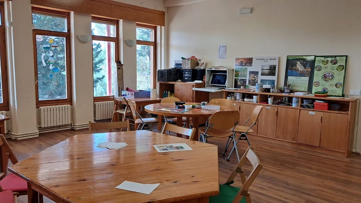 Interior del Aula Medioambiental de La Grajera con mesas de madera, sillas y estanterías con materiales educativos