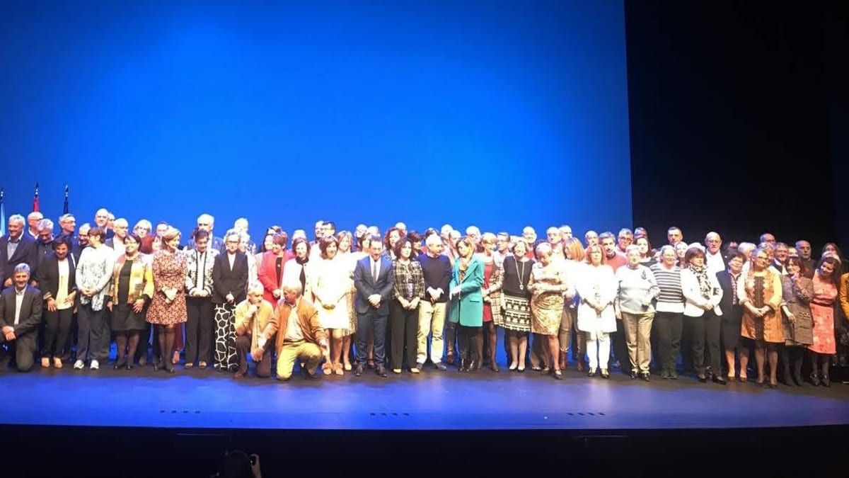Grupo de profesores y profesoras jubilados en el escenario del Teatro de la Laboral de Gijón durante el acto de homenaje
