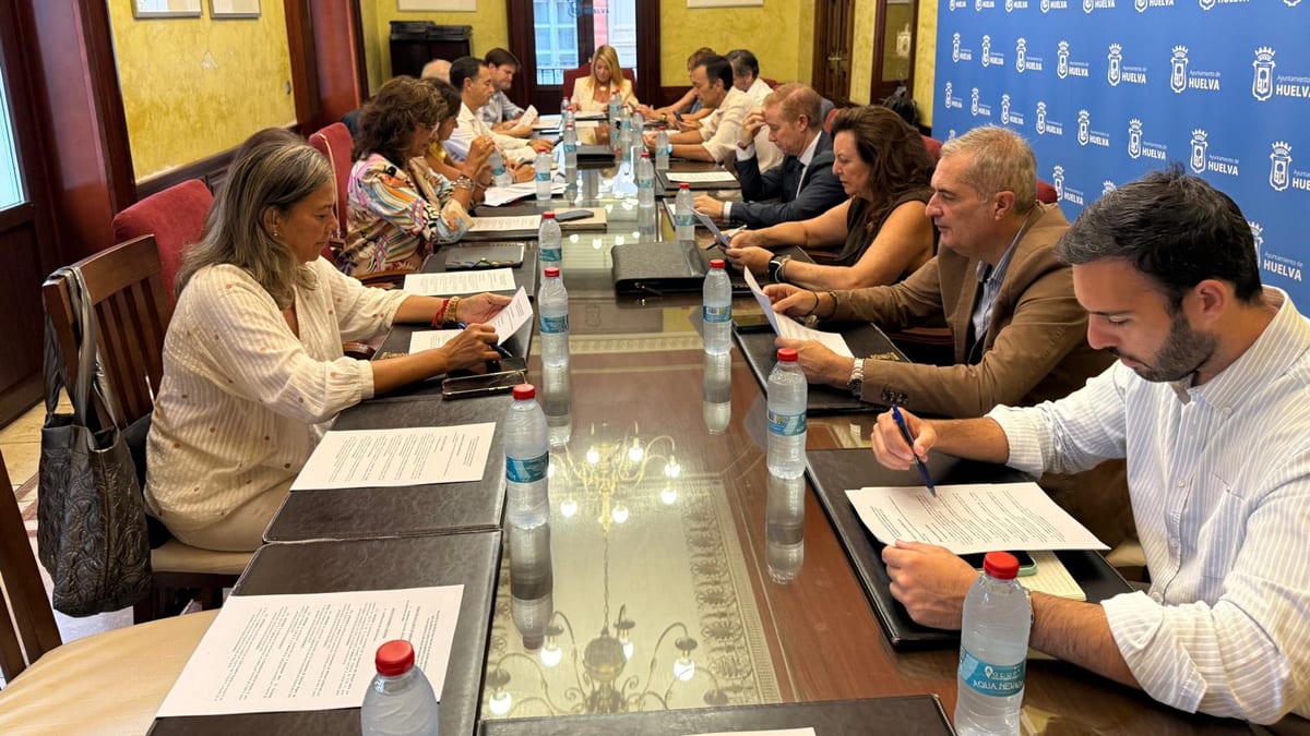 Reunión de la Junta de Gobierno Local de Huelva en sala de conferencias con paredes amarillas