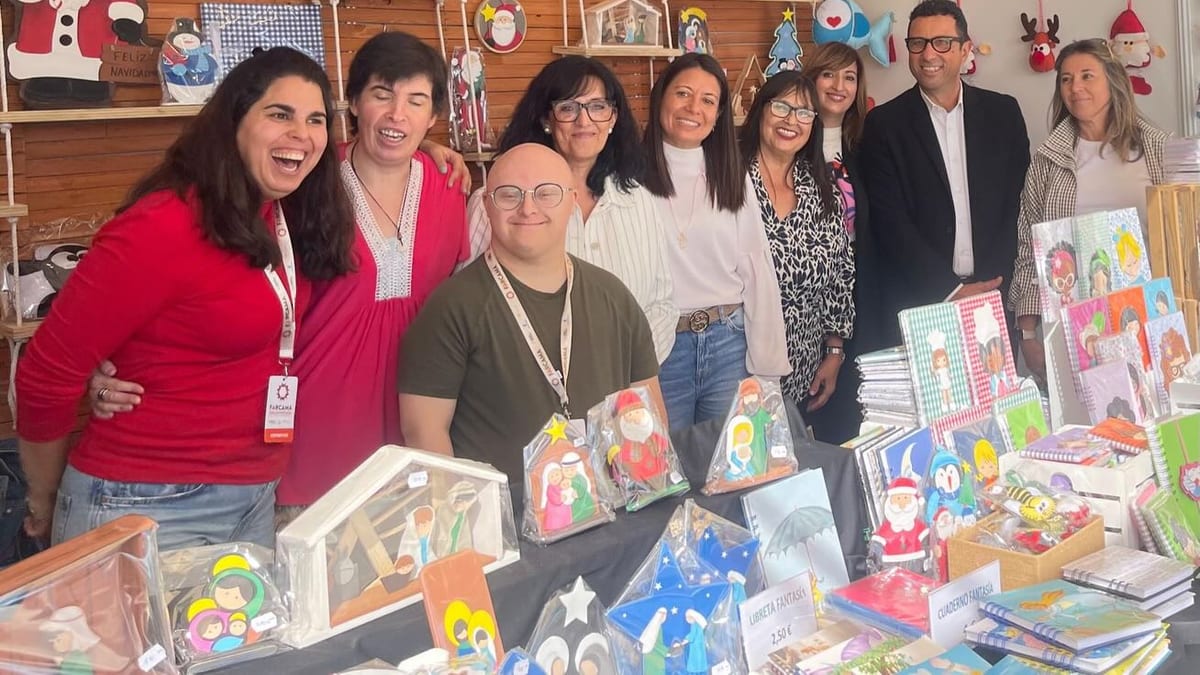 Grupo de personas posando frente a decoración navideña en el stand del Centro Ocupacional Valenzana en la feria FARCAMA de Toledo