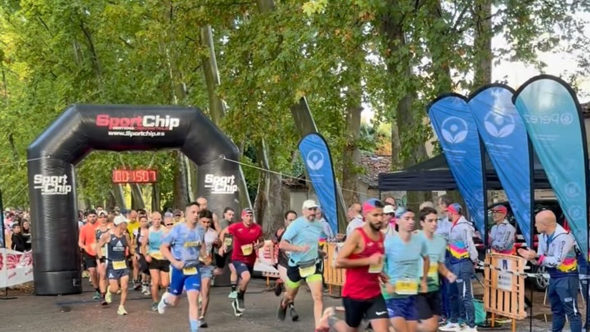 Participantes en el IV Trail El Peluca de Aranjuez en la salida de la carrera con arco inflable negro y banderas azules