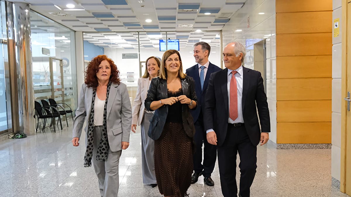 Grupo de personas caminando por un pasillo de un edificio institucional